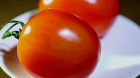 Two tomatoes  turns on  white plate. Close up Video stock 35916036