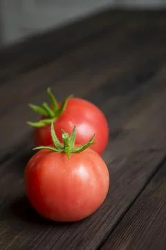 Two tomatoes on a wooden table. On the table are two red tomatoes with tails. Foto stock