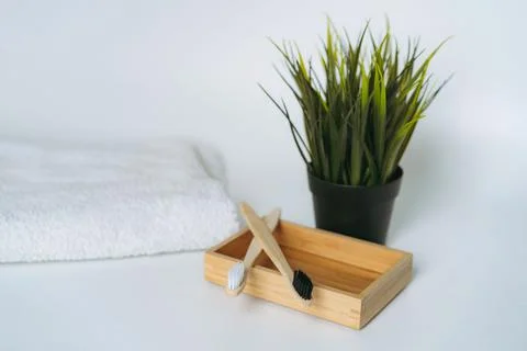 Two toothbrushes on bamboo case. white towel and artificial flower on white b Fotos de archivo