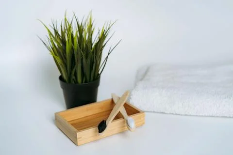 Two toothbrushes on bamboo case. white towel and artificial flower on white 写真素材
