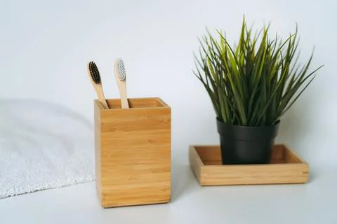 Two toothbrushes in bamboo folder. white towel and artificial flower on white Stock-Fotos