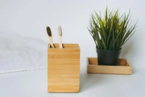 Two toothbrushes in bamboo folder. white towel and artificial flower on white Stock-Fotos