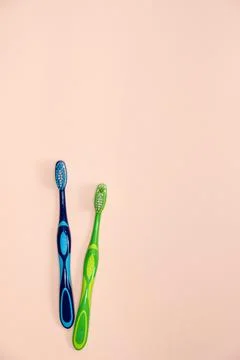Two toothbrushes on a beige background, top view, space for text. Stock Photos