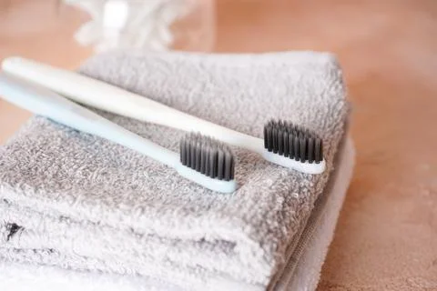 Two toothbrushes with black shield and towels, on a beige background Stock Photos