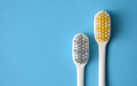 Two toothbrushes on a blue background close-up. Stock Photos