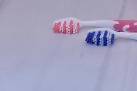 Two toothbrushes close up - one blue and one pink with on gray surface with c Stock Photos