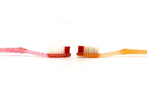 Two toothbrushes facing each other on a white background representing denta.. Stock Photos