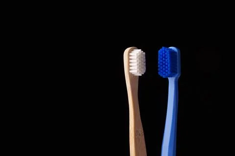 Two toothbrushes, one made of bamboo and the other made of blue plastic, on a Stock Photos