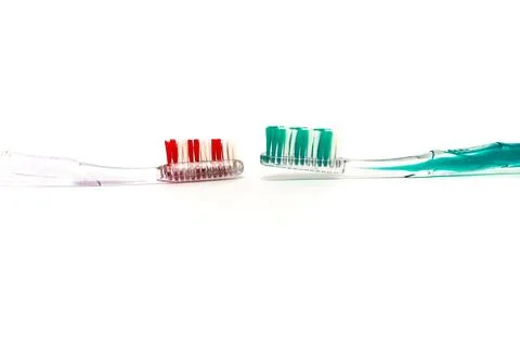 Two toothbrushes, one red and one green, face each other on a white backgro.. Foto stock