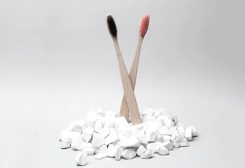 Two toothbrushes with toothpaste standing in a pile of white stones Fotos Stock