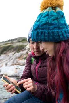 Two tourists are looking at a map on a smartphone, two women are traveling to Stock Photos