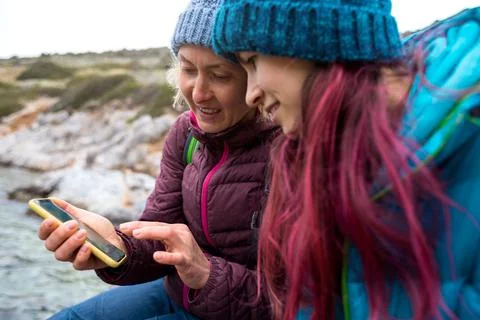 Two tourists are looking at a map on a smartphone, two women are traveling to Stock Photos