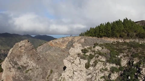 Two tourists are observing the landscape of La Gomera from the back of a cliff 스톡 동영상 320770705