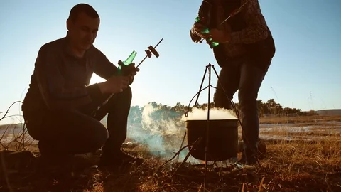Two tourists beer are sitting lifestyle by bonfire party in nature camping Stock Footage 88818994