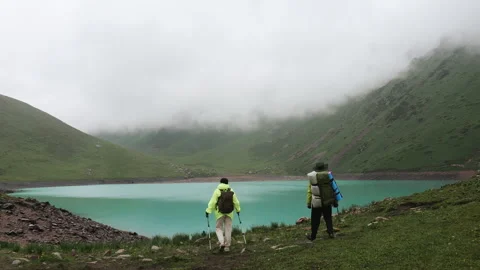 Two tourists climbed up to a mountain lake and are happy with their achievement. 스톡 동영상 313102798