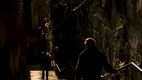 Two tourists coming down the narrow staircase between two buildings Stock Footage 143392407