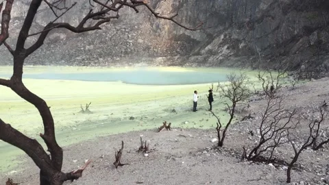 Two Tourists Exploring a Beautiful Volcanic Crater Lake with Dead Trees Video stock 346933615