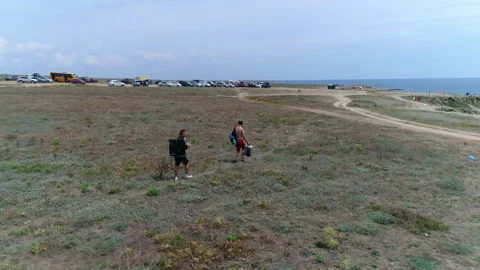 Two tourists go through the field to the sea Video stock 103089558