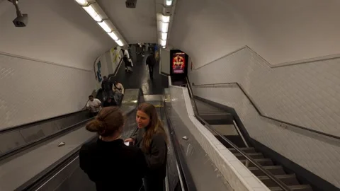 Two tourists going up an escalator in a Paris Metro station Stock Footage 313572491