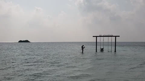 Two tourists have fun and take pictures at dusk in Maldives with water swing Stock Footage 280795604