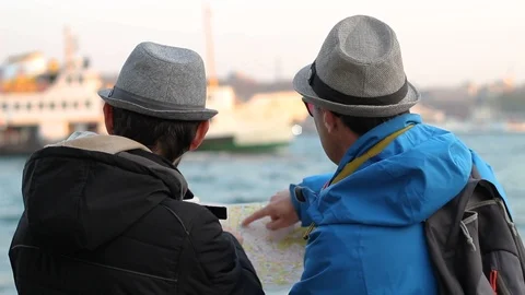 Two tourists man examines map on sea coast Vídeos de archivo 106290691