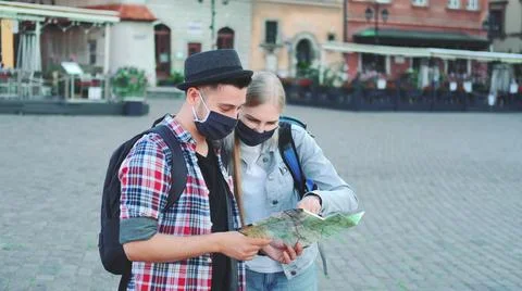 Two tourists in protective masks using map on central city square Stockfoto's