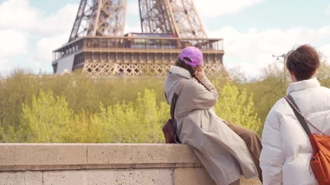 Two Tourists Sitting On Wall Taking Photos Of Eiffel Tower In Paris, Medium Shot Stock Footage 340180864
