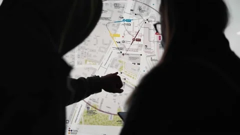 Two tourists stand in front of a map of the city in a dark passage Stock Footage 154135987