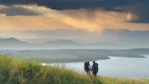 The two tourists standing on mountain top on beautiful river background Video stock 159833026