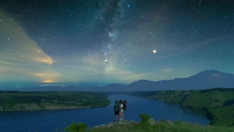 The two tourists standing on the mountain top above night river Stock Footage 159840613