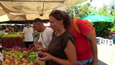 Two tourists tasting fresh plums at fruit stall in Fethiye market Video stock 344972711