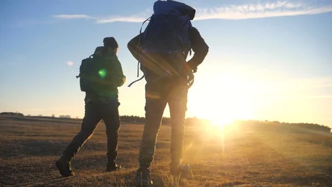 Two tourists teamwork with backpacks slow motion walking go silhouette in the Stock Footage 129601487