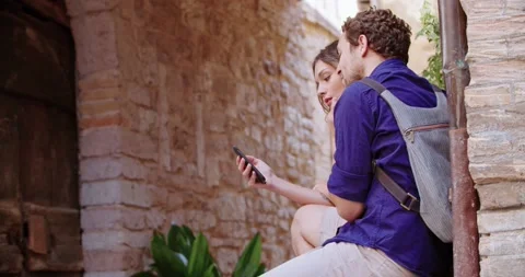 Two tourists using smartphone to search amenities or landmarks in rural town Vídeos de archivo 135959079