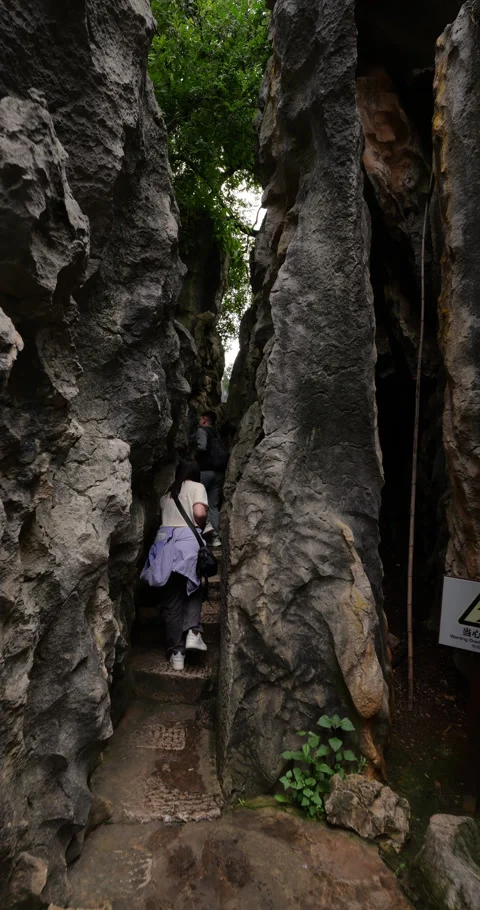 Two tourists walk in narrowing passage at Shilin Stone forest, follow shot Stock Footage 329597560