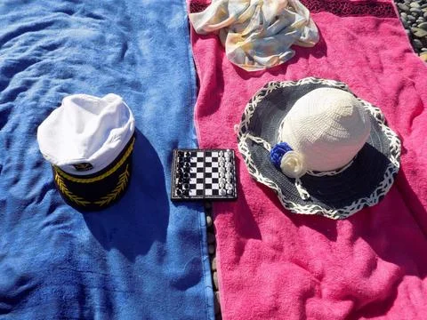 Two towels spread, a captain's hat, a straw hat and a Chessboard with figures Stock Photos