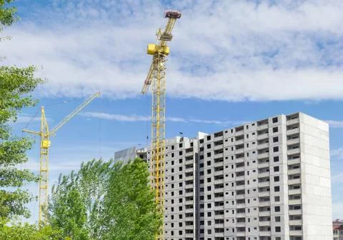 Two tower cranes against of multi-story residential building construction Stock Photos