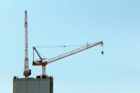 Two tower cranes over the top of a high-rise building under construction agai Stock Photos