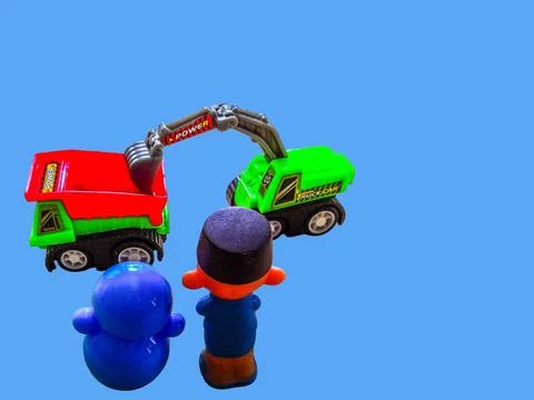 Two toy figures are looking at a toy excavator and a toy truck Stock Photos