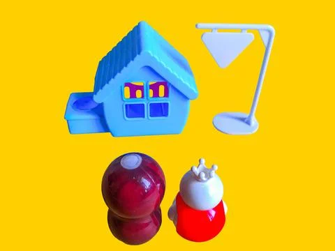 Two toy figures are looking at a toy house and a white toy sign Stock Photos