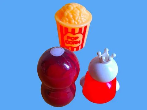 Two toy figures are looking at toy pop corn on a blue background Stock Photos