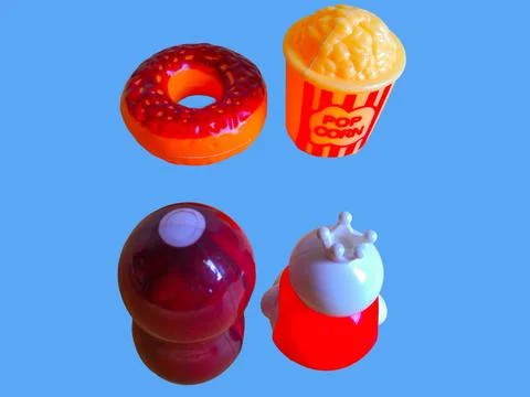 Two toy figures are looking at toy pop corn and a toy donut Stock Photos