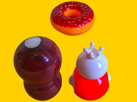 Two toy figures are looking at a toy donut on a yellow background Stock Photos