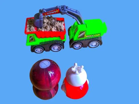 Two toy figures are watching a toy excavator putting sand into a toy truck Stock Photos