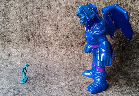 Two toy figures facing each other. One much bigger than the other Stock Photos