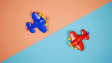 Two toy planes move towards one another diagonally over blue-coral background Stock-Footage 102672415