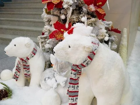 Two toy polar bears in beautiful scarves are sitting near the Christmas tree Stock Photos