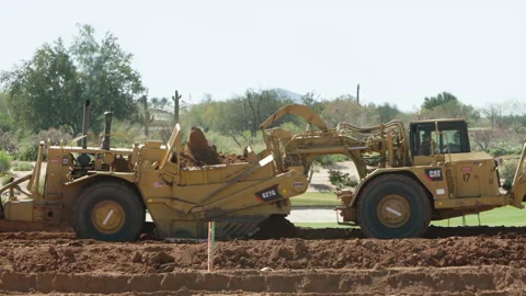 Two Tractor Scrapers linked to each other scraping earth Stock Footage 217516988