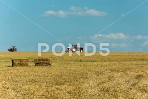Two tractors driving across the stubble field Stock Photos