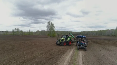 Two Tractors Working in Field, Sowing Process, Seeding Soil by Crops of Wheat Stock Footage 127980213