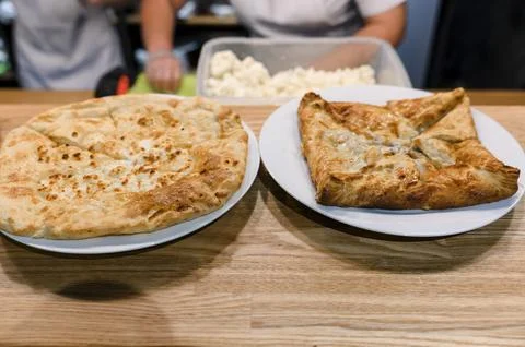 Two traditional flatbreads served on white plates, wooden table background Stock Photos